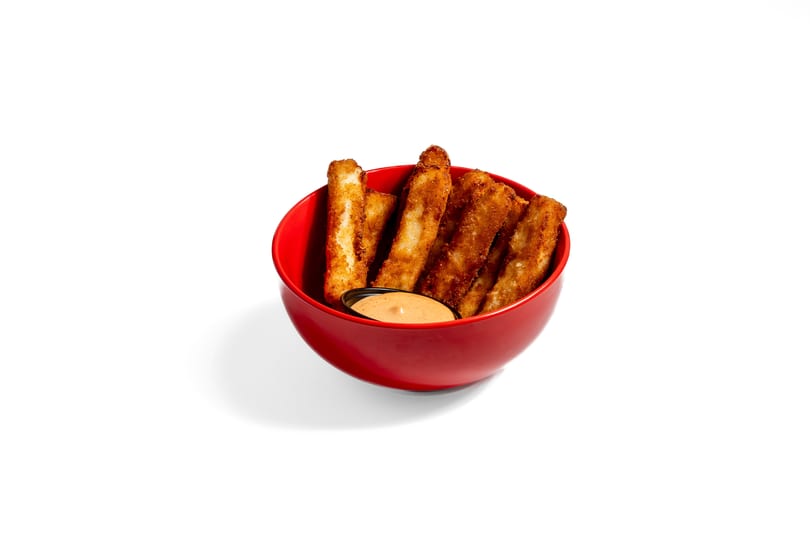Crispy fried mozzarella sticks in a red bowl with a side of dipping sauce.